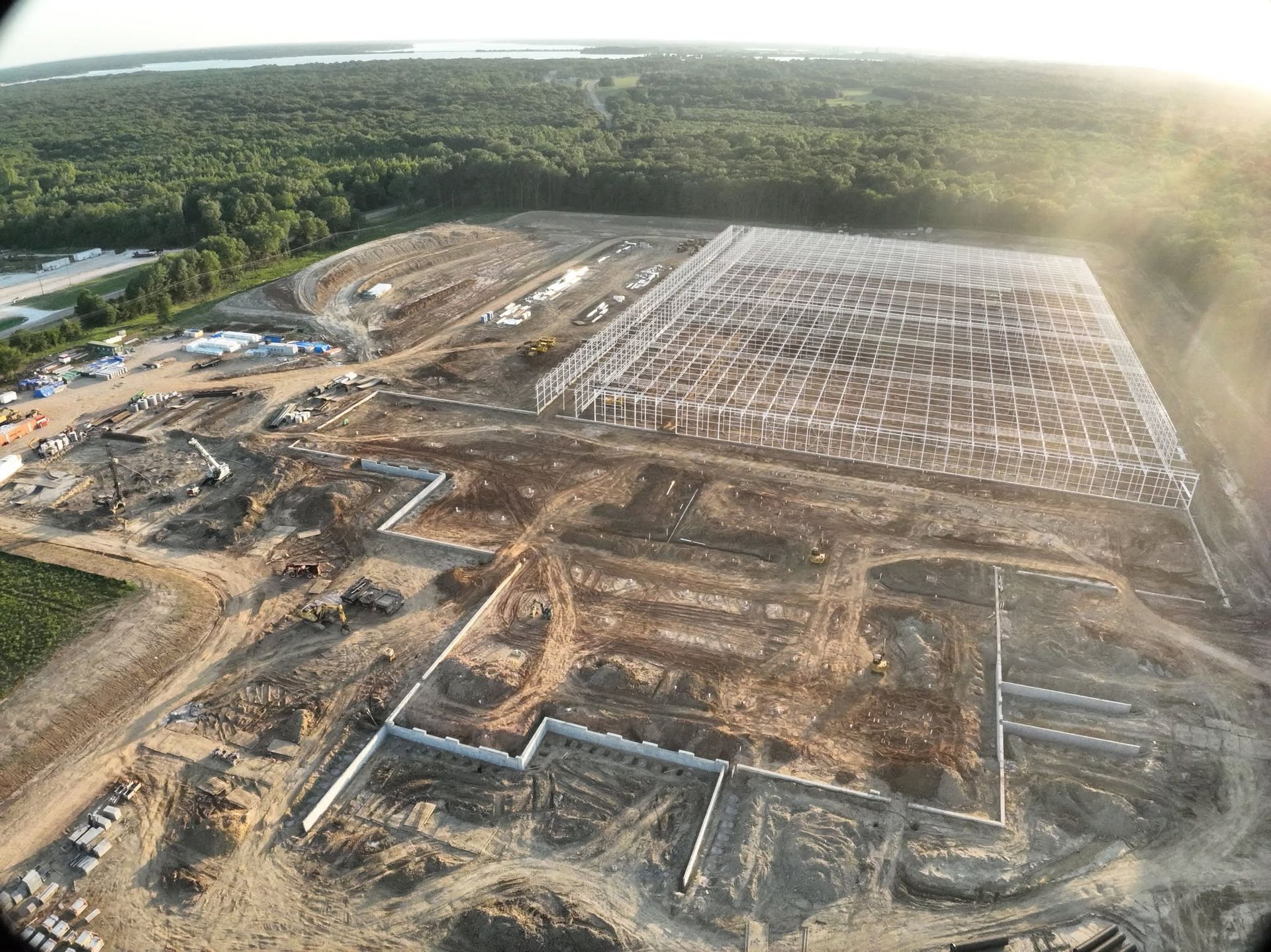 Aerial view at golden hour of a steel-frame warehouse under construction on a graded pad
