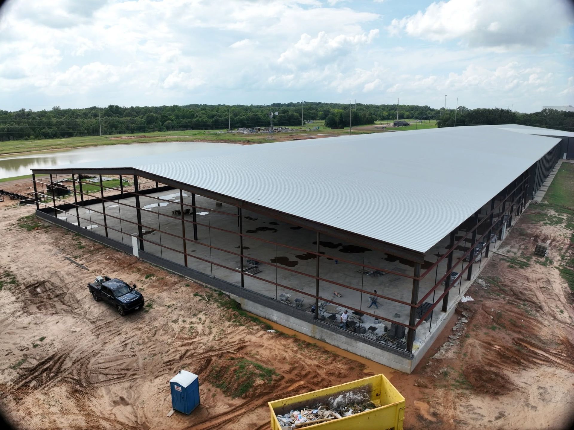 Aerial view of a long-span steel building with the roof deck part way on