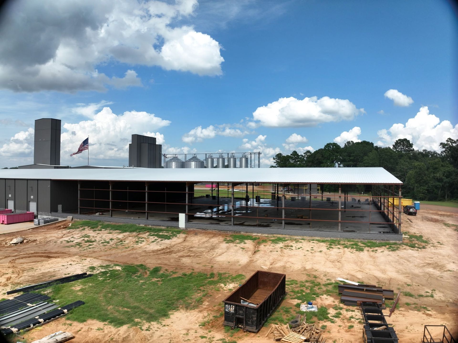 Aerial view of a near-complete commercial building with an entry canopy and silos behind
