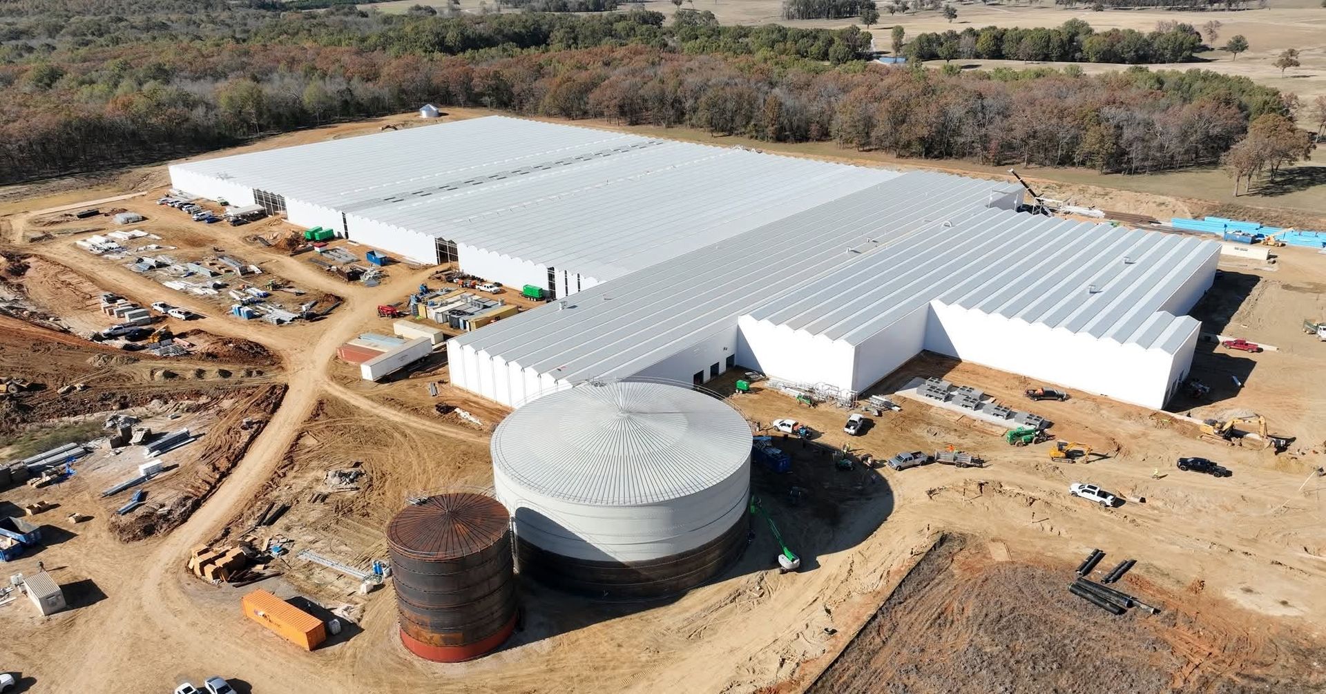 Aerial view of a completed white industrial building complex with a concrete tank