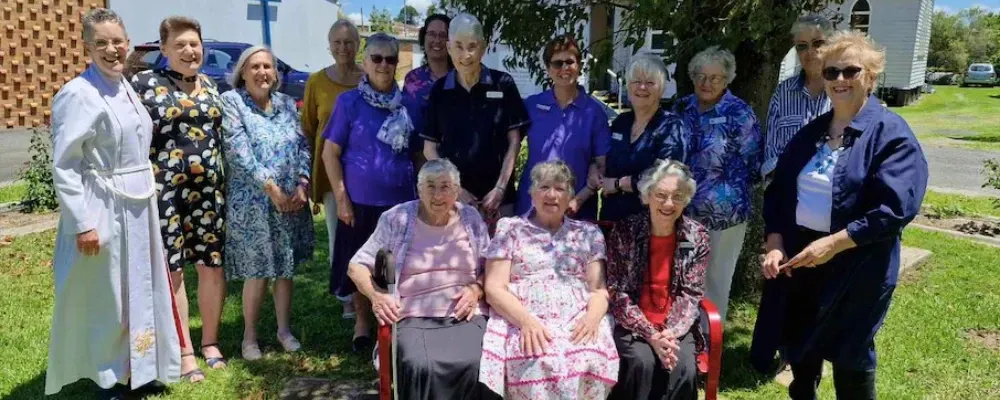 A group of elderly women are posing for a picture in front of a church.