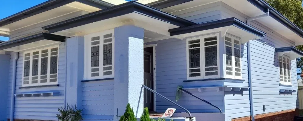 A blue house with white windows and a black roof