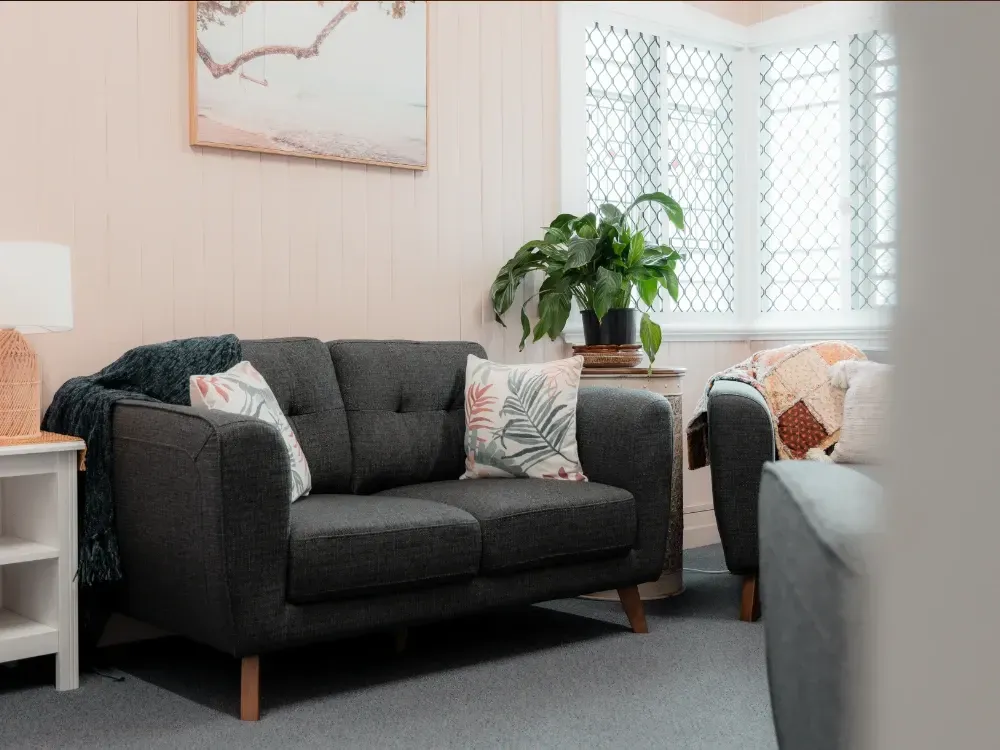 A living room with a couch , chairs , and a plant.
