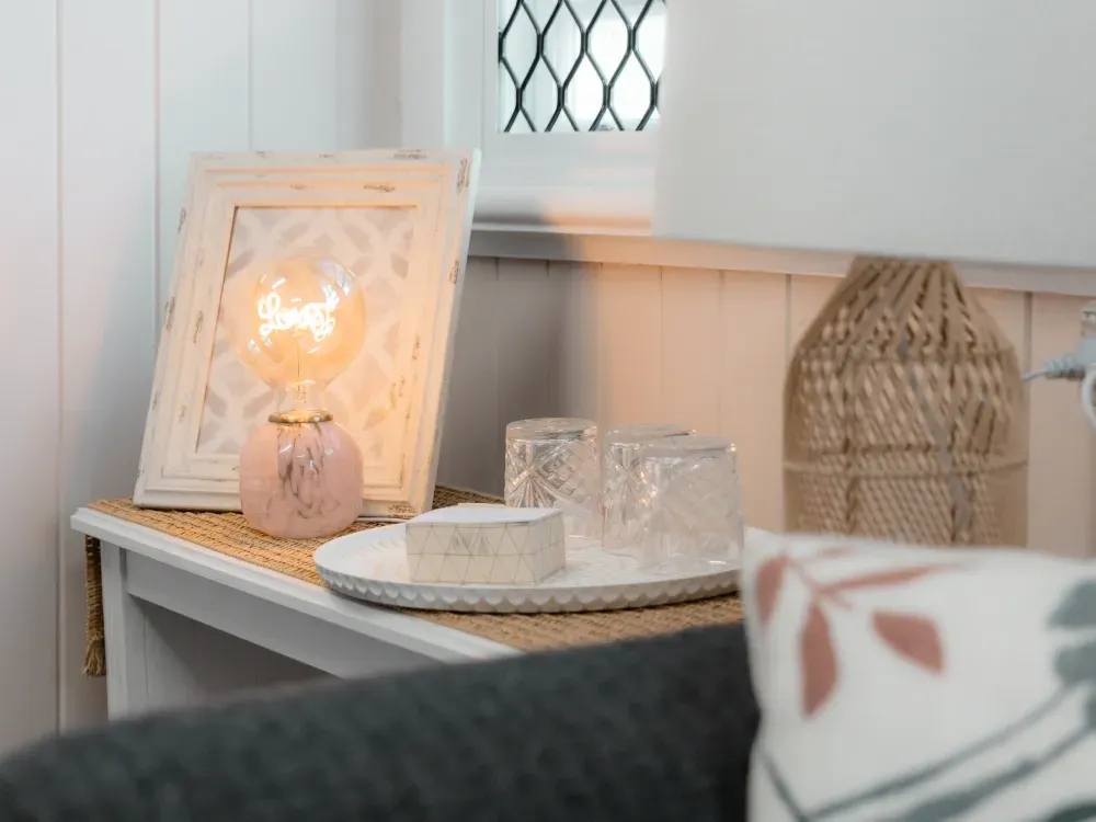 A table with a lamp and a picture on it in a living room.