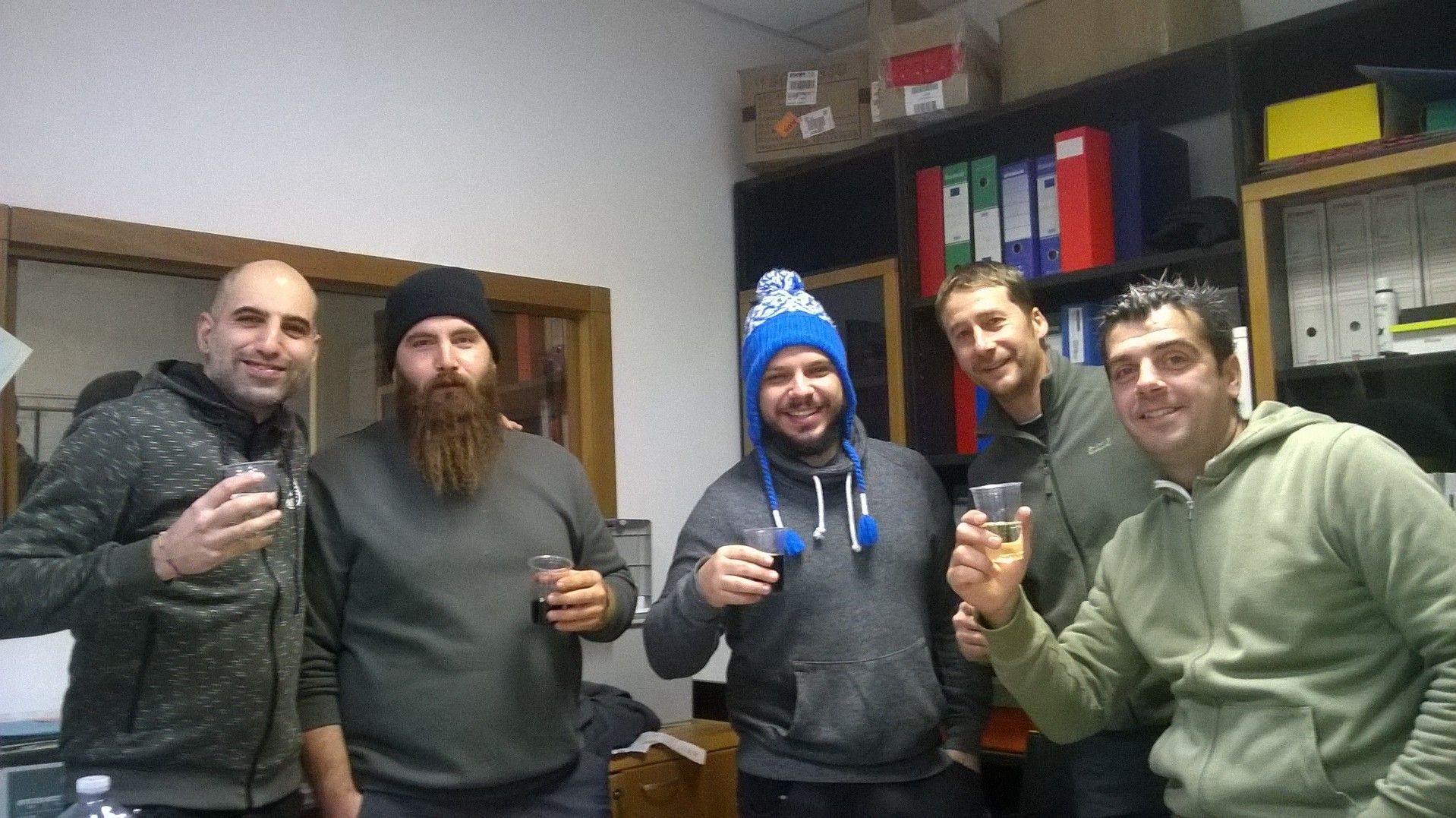 Cinque persone posano in un ripostiglio, sorridenti e con in mano dei drink.