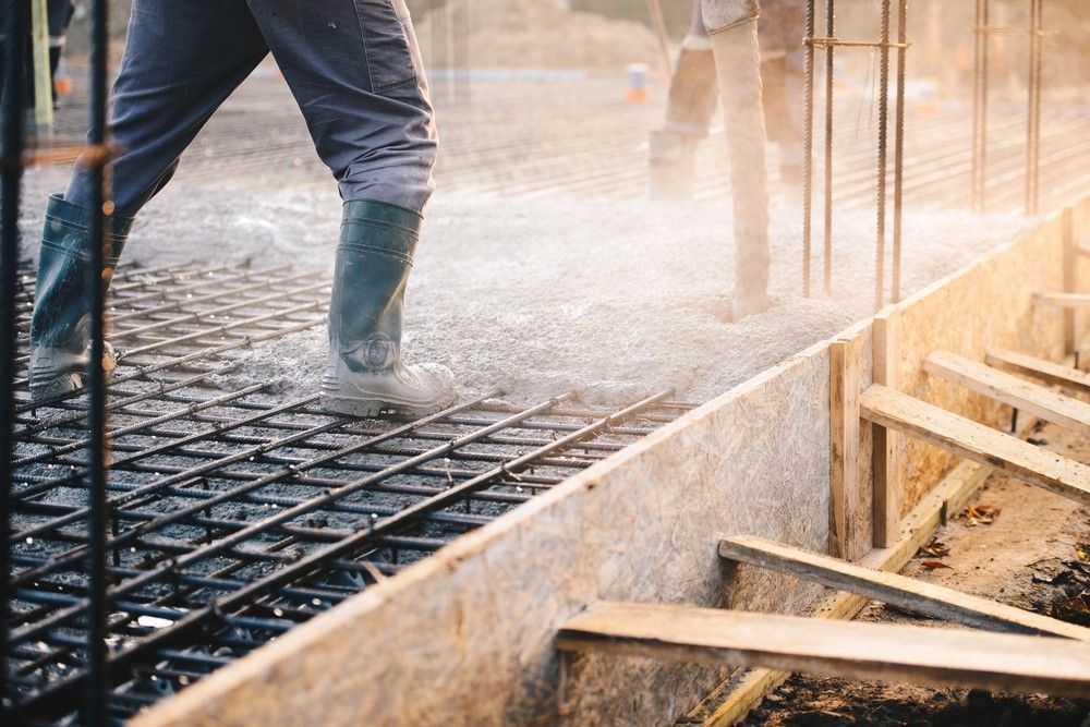A Man Is Pouring Concrete On A Construction Site — Core Concrete in Cairns, QLD