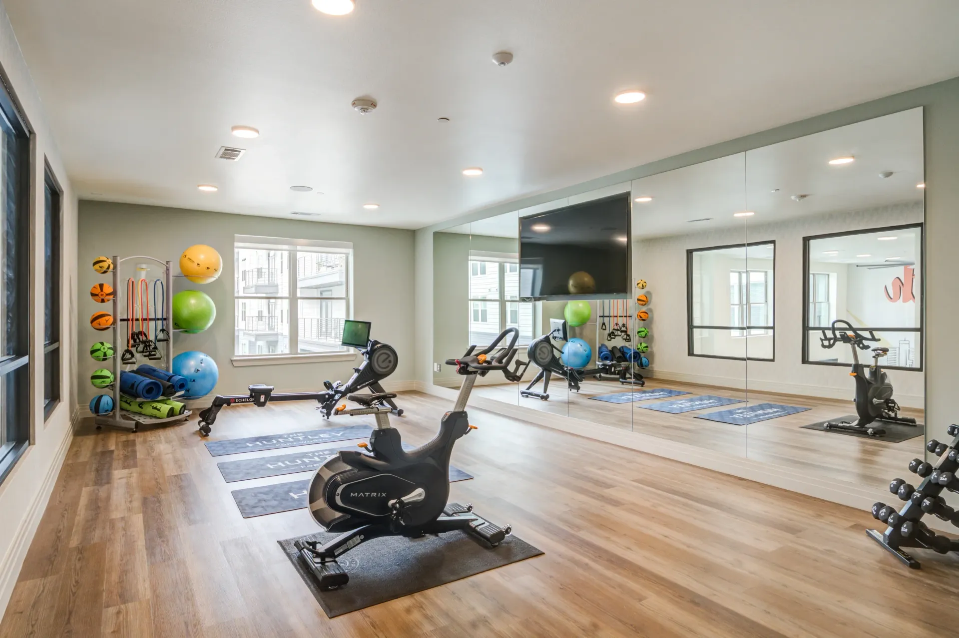 Fitness center with cardio machines, weights, and yoga mats.