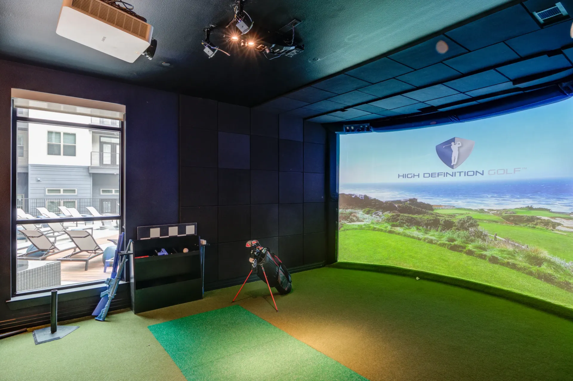 Indoor golf simulator with a screen displaying a golf course and a golf bag.