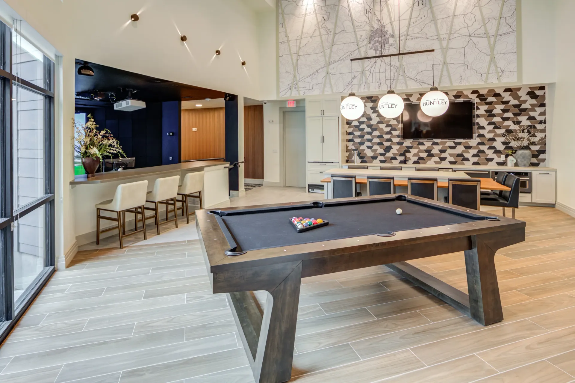 Community game room with a pool table, bar seating, and a large map mural.