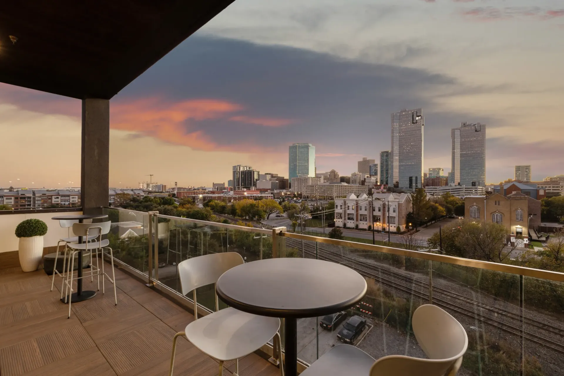 Balcony overlooking a city skyline at dusk with outdoor seating.