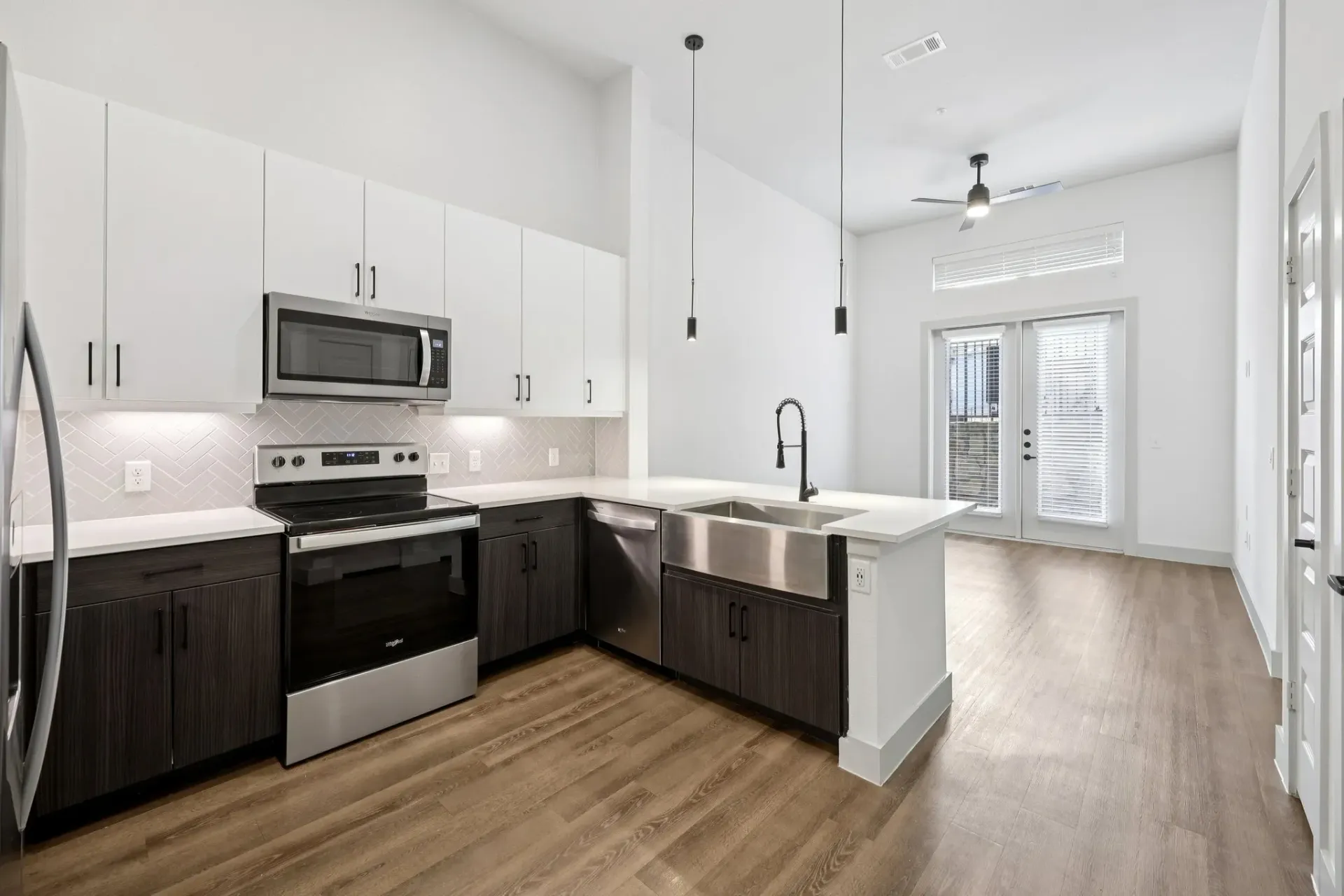 Modern kitchen with white and dark wood cabinetry, stainless steel appliances, and a farmhouse sink.