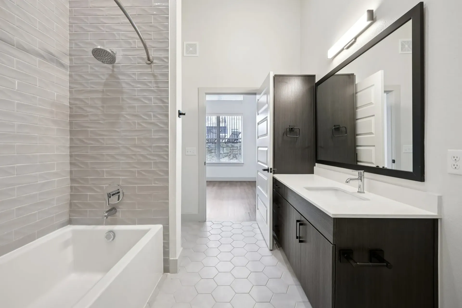 Modern bathroom with a soaking tub and walk-in shower, vanity with a large mirror, and hexagonal floor tiles.