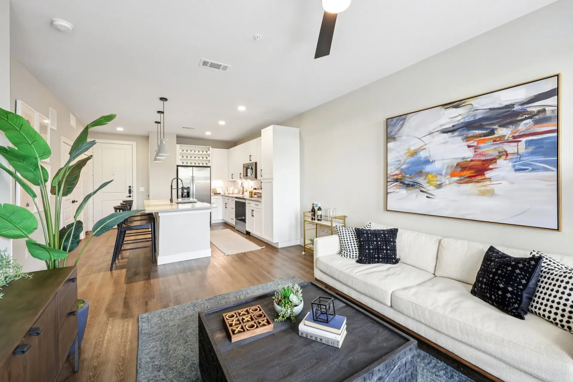 Modern living room and kitchen area with a white couch, coffee table, and island.