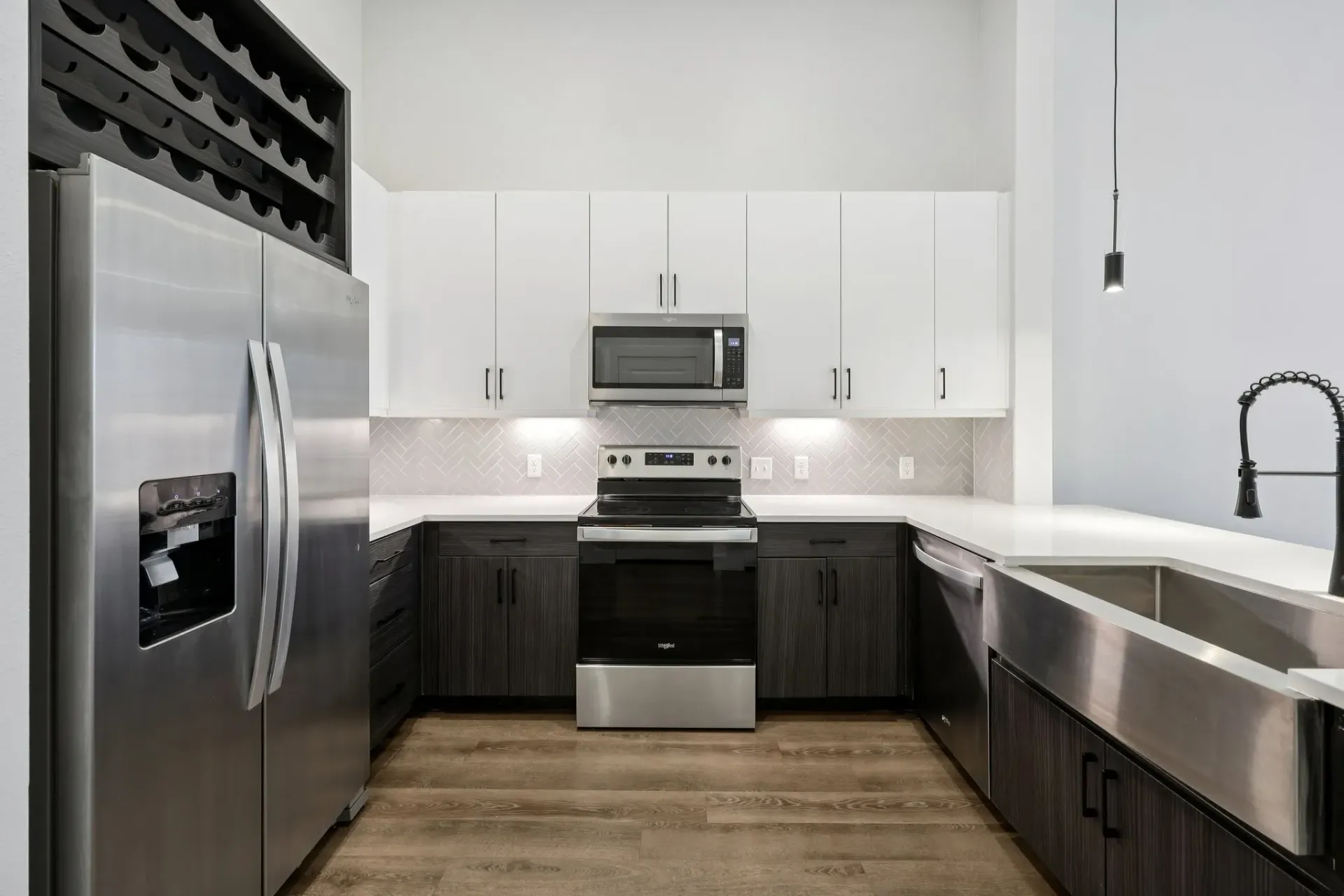 Modern kitchen with stainless steel appliances, white countertops, and dark wood cabinets.
