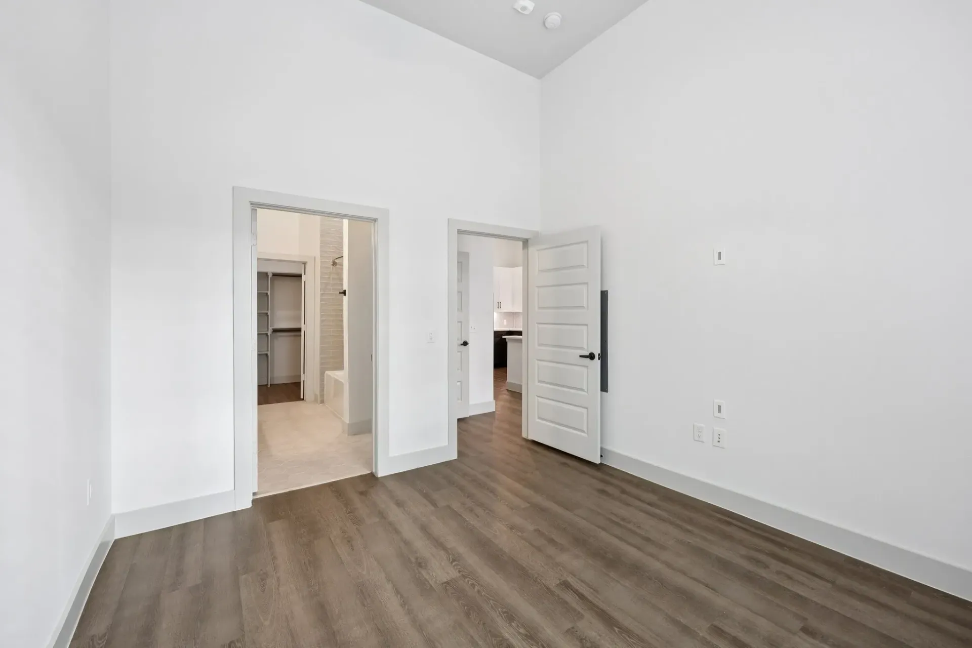 Empty apartment bedroom with view into bathroom and closet.