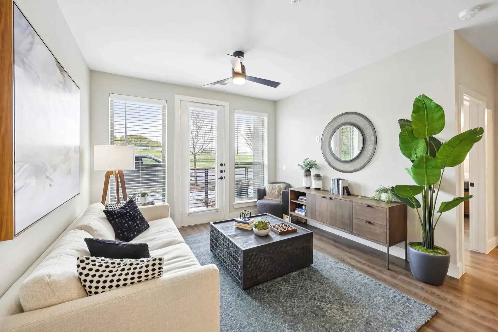 Modern living room with a plush sofa, decorative coffee table, and large windows.