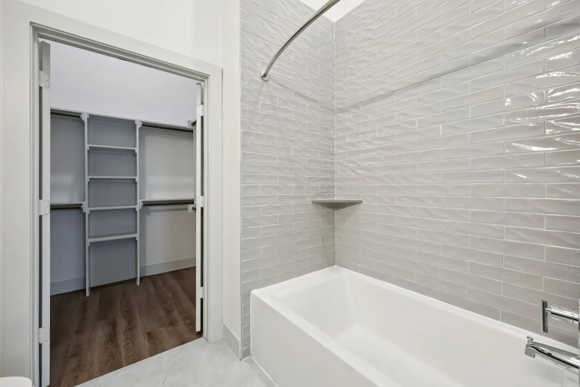 View of a bathtub and a walk-in closet with shelves.