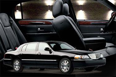 Black Lincoln Town Car sedan with dark interior; wooden trim.