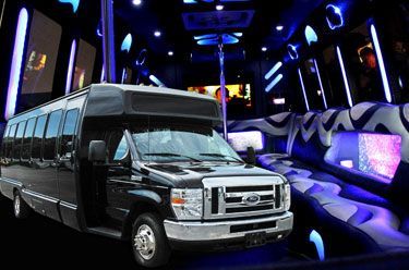 Black party bus interior with blue lights and seating.