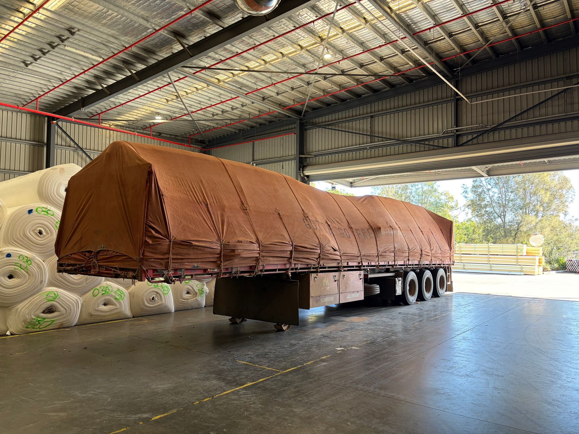 Blue tarp-covered semi-trailer truck in a warehouse.