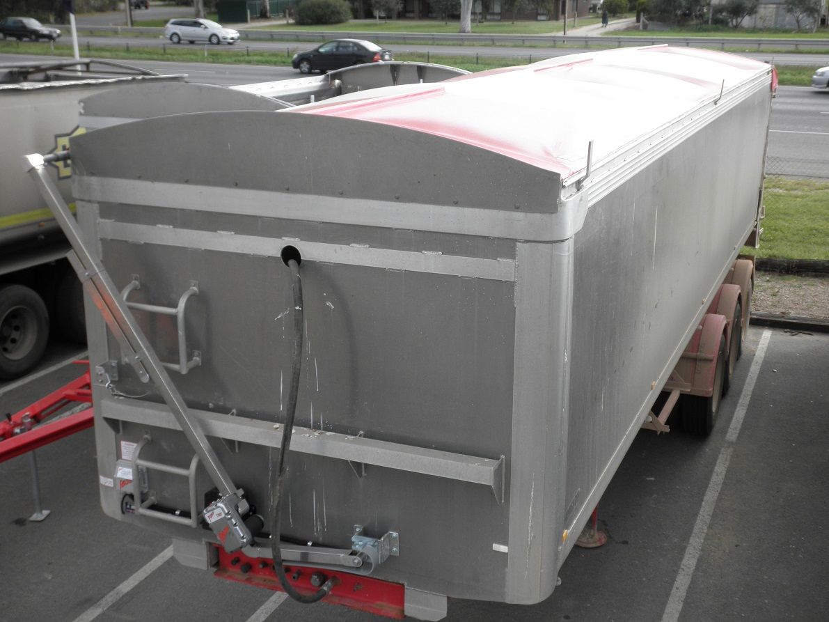 Blue tarp-covered semi-trailer inside a warehouse, connected to a truck with blue and white paint.