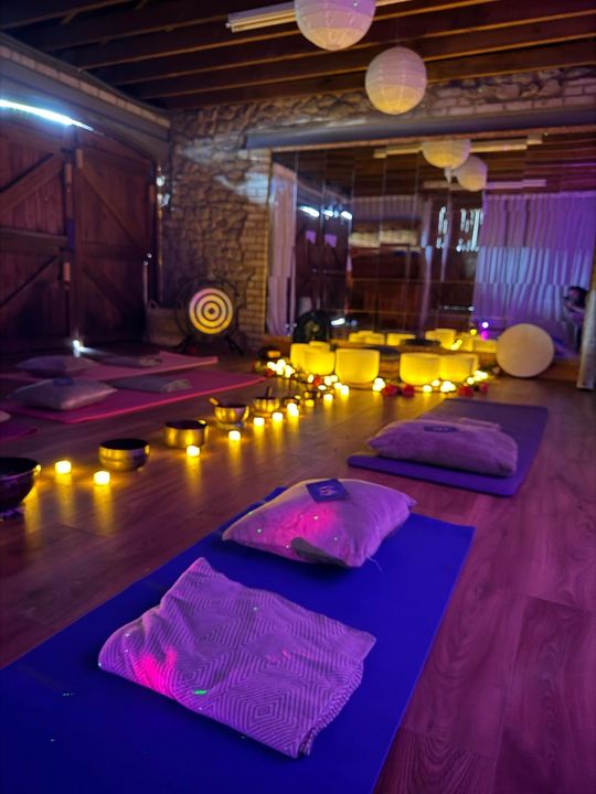 Cozy candlelit yoga studio with mats, pillows, lanterns, and purple ambient lighting