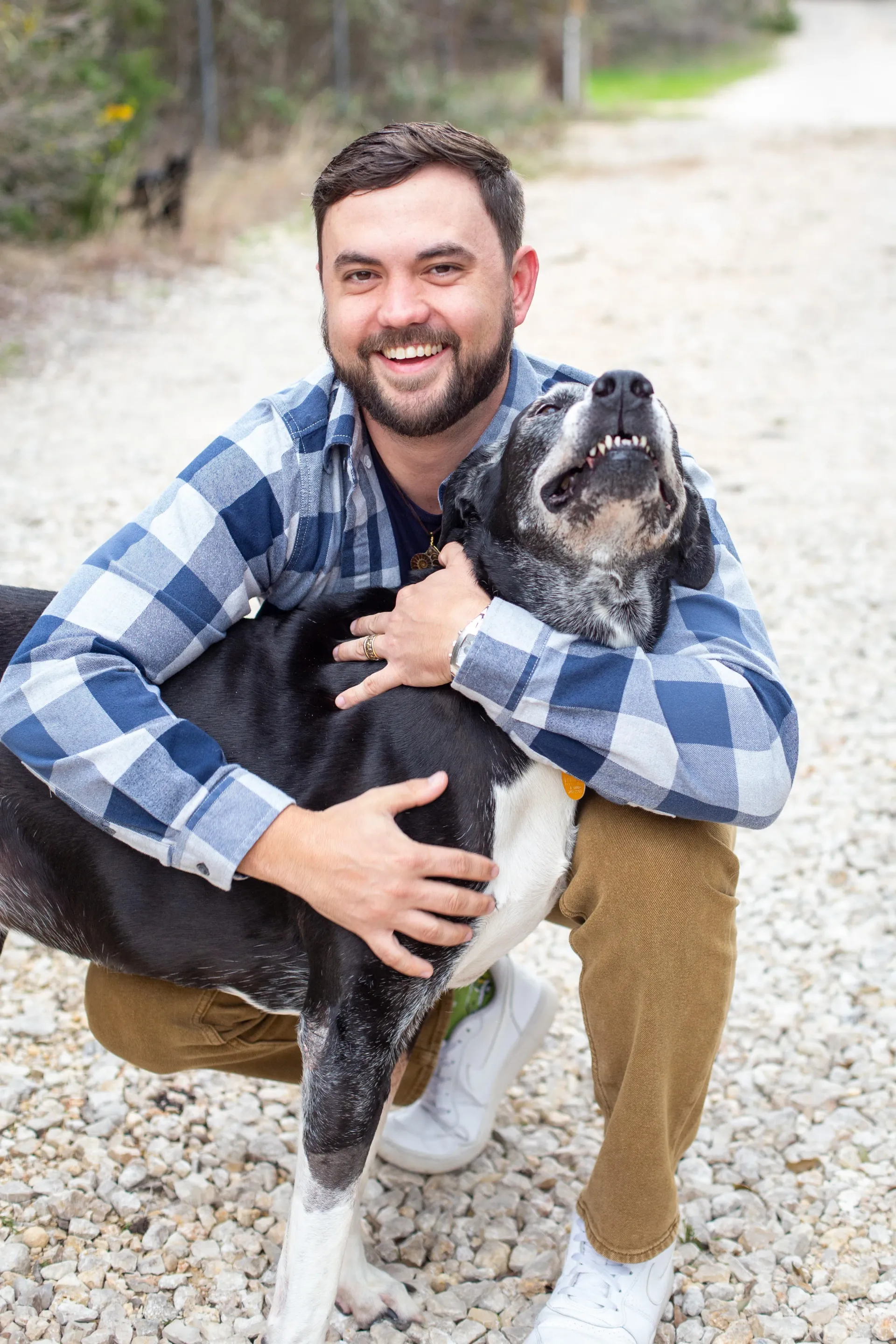 A man is kneeling down with a dog on his lap.