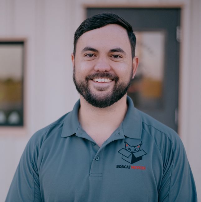 A man with a beard and a bobcat logo on his shirt