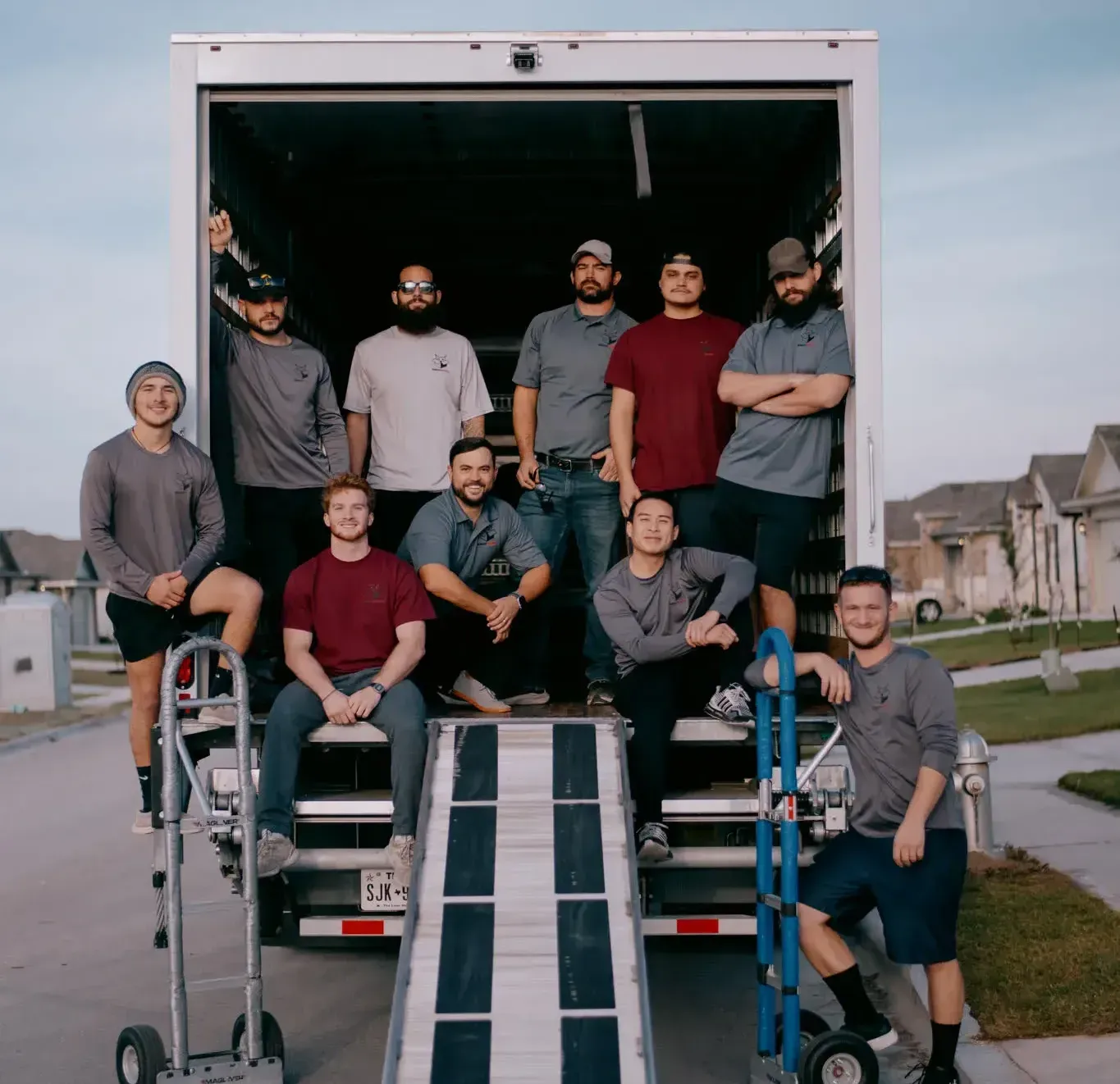 A group of men are posing for a picture in front of a moving truck.