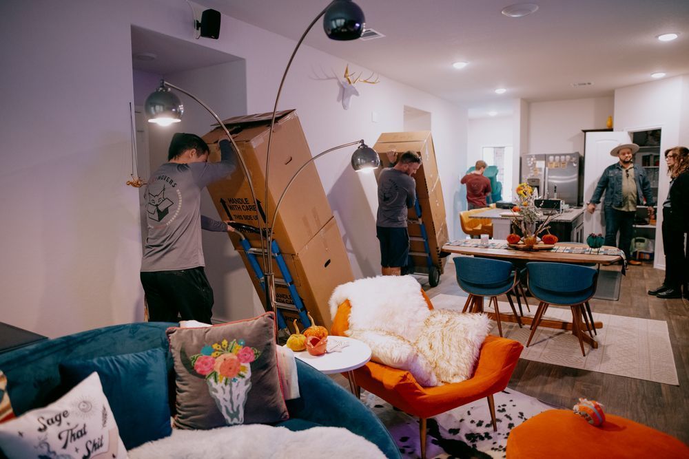 A group of people are moving boxes in a living room.