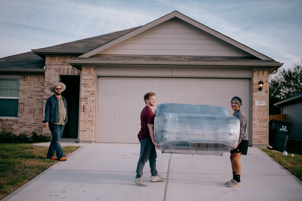 A group of people are carrying a car in front of a house.