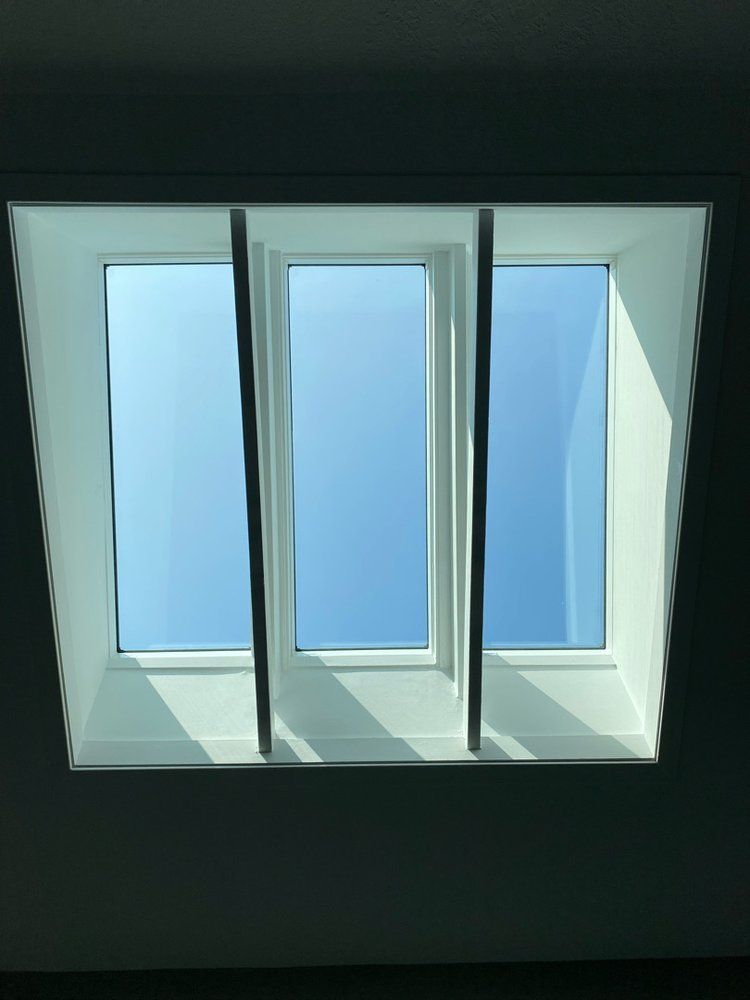 A skylight with three windows looking out to a blue sky