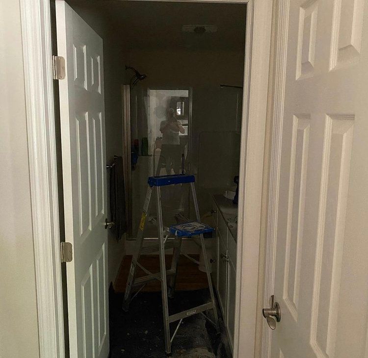 A ladder is sitting in a bathroom next to a door
