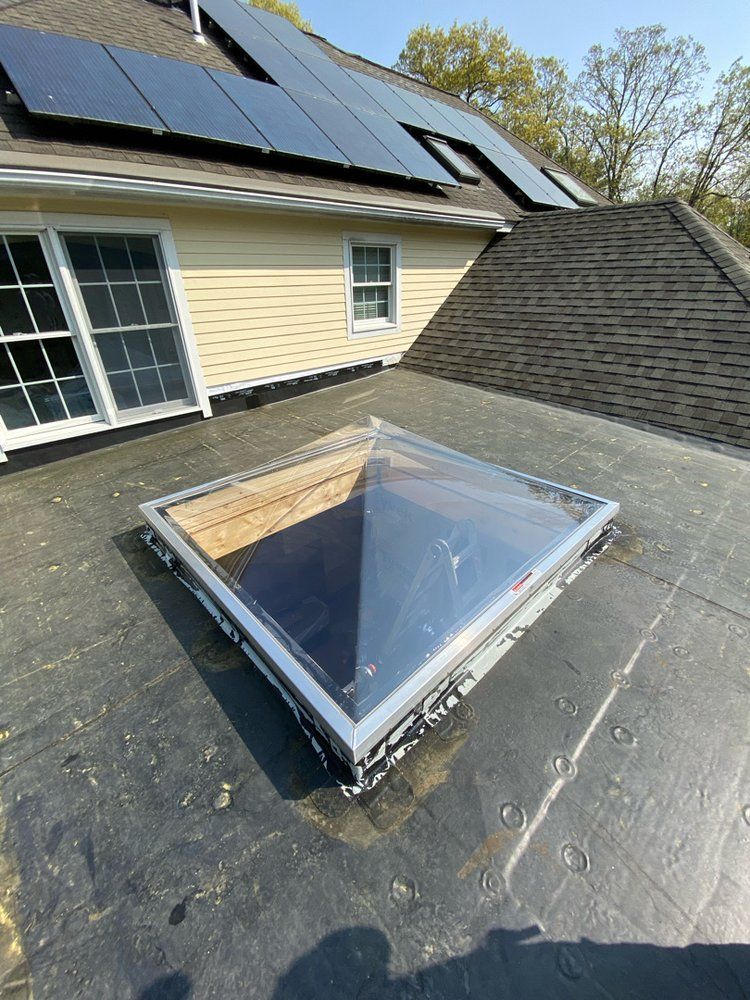 A skylight on the roof of a house with solar panels