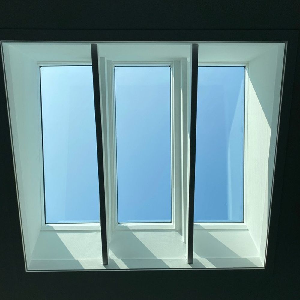 A skylight with three windows and a blue sky behind them