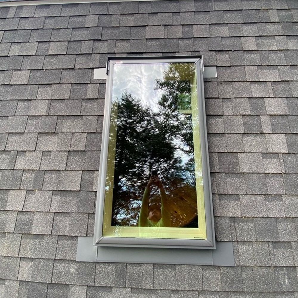 A skylight on a roof with a reflection of trees