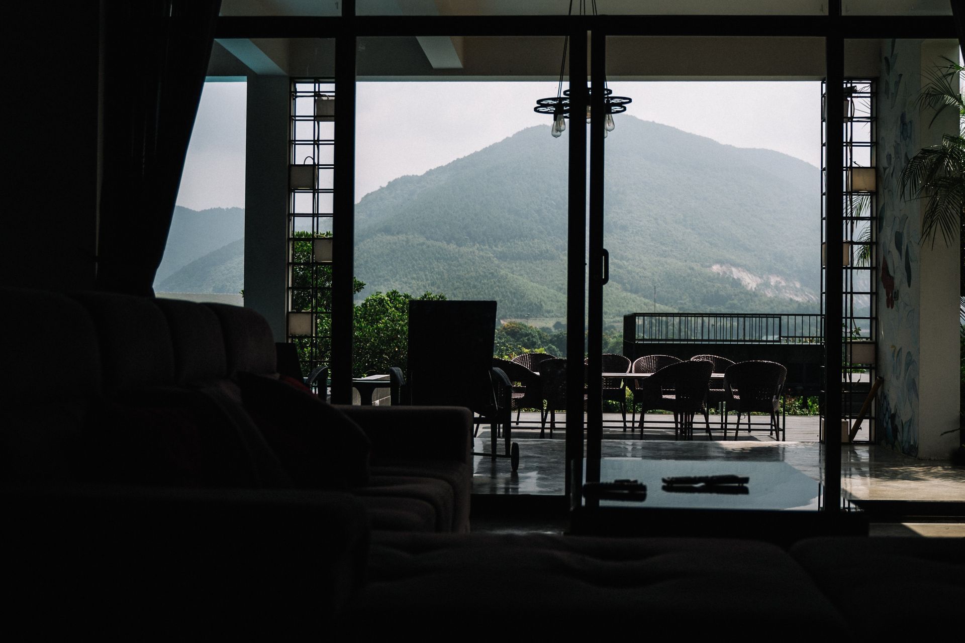 Dark living room overlooking a patio and misty mountain through open glass doors