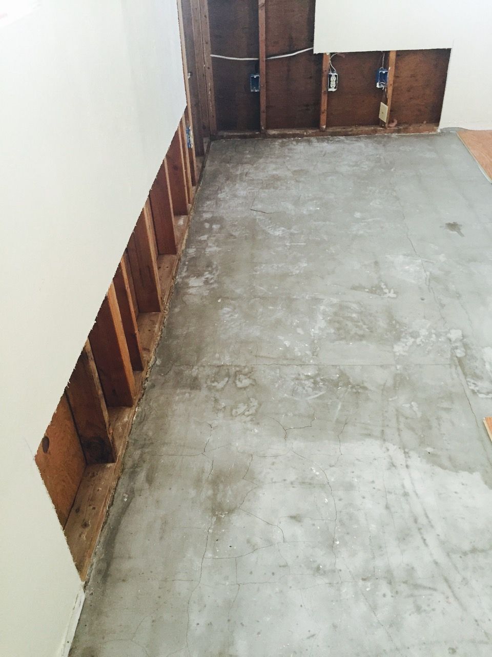 Interior room with exposed studs and concrete floor, showing construction or damage.