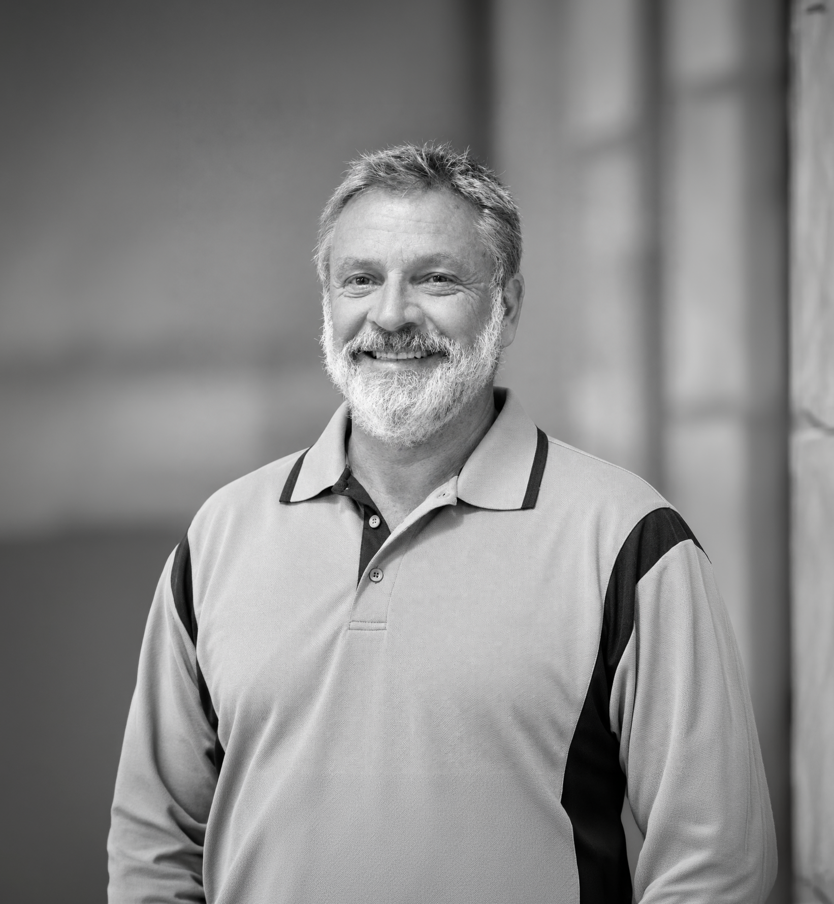 Brett (man) man with gray beard in a light polo shirt, standing against a blurred background.
