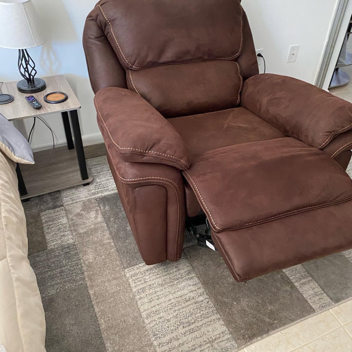 Brown recliner chair with footrest beside a small side table in a living room.