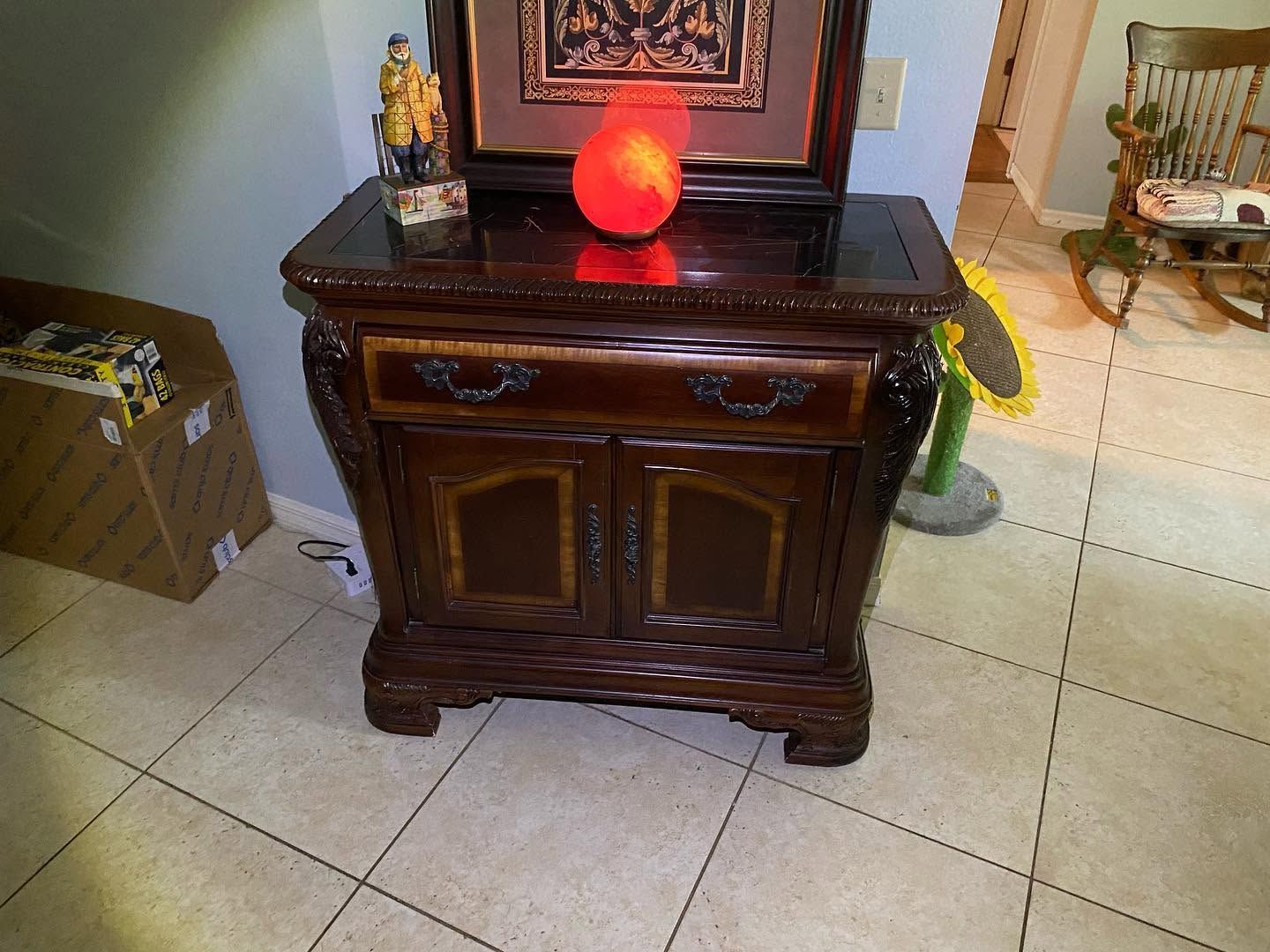 Dark wooden cabinet with glowing red lamp in a tiled room