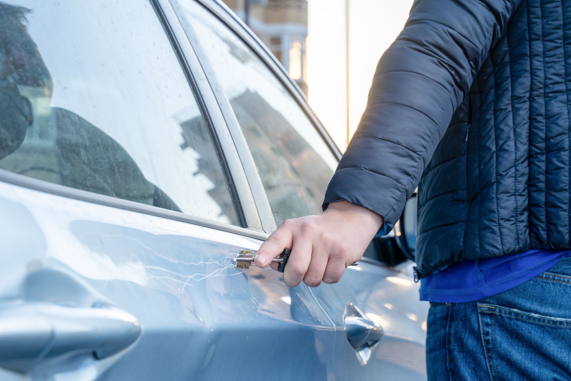 Person scraping frost off a blue car window with a hand scraper.