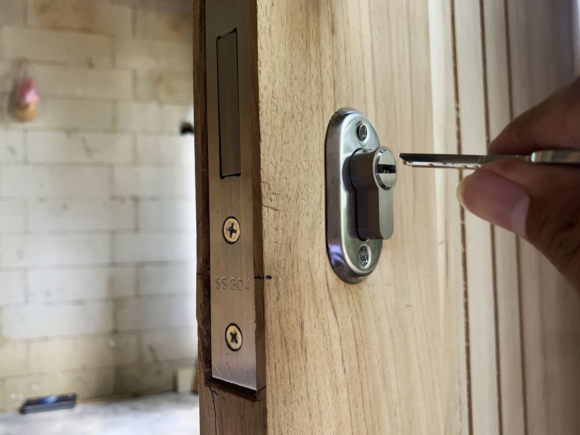 Hand turning a key in a wooden door lock, with a room visible in the background