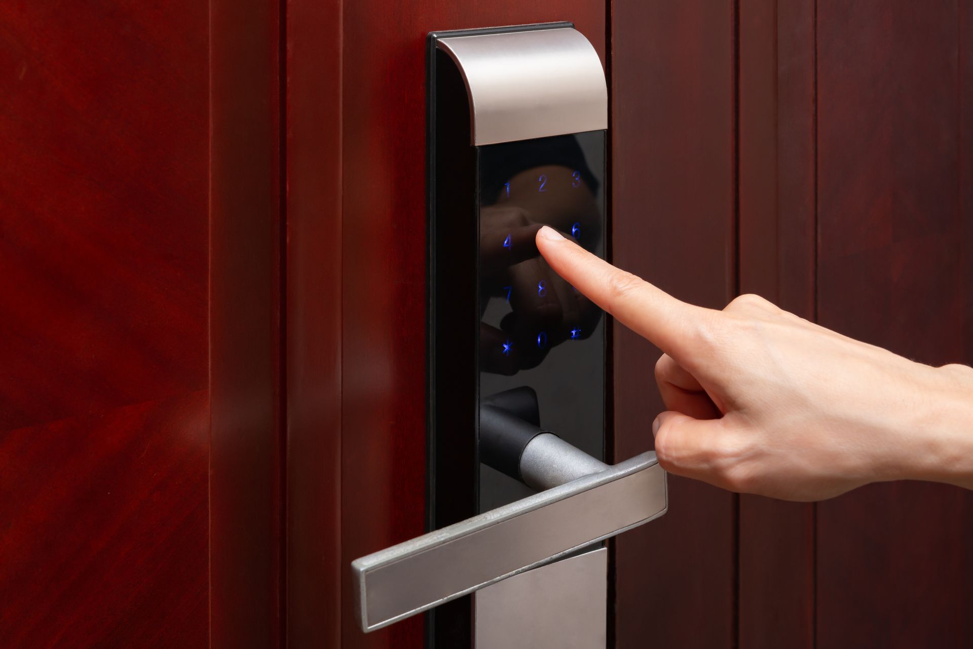 Hand pressing a touchless door handle on a red wooden door