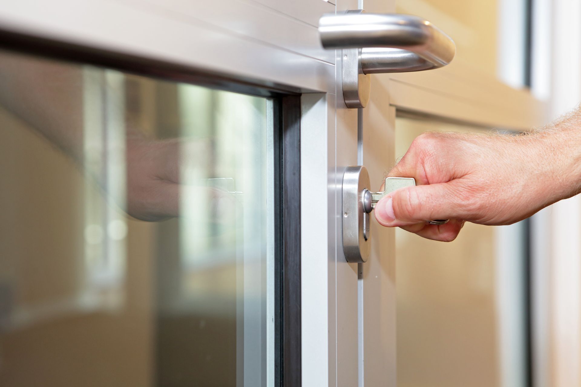 Hand turning a silver door handle on a glass door
