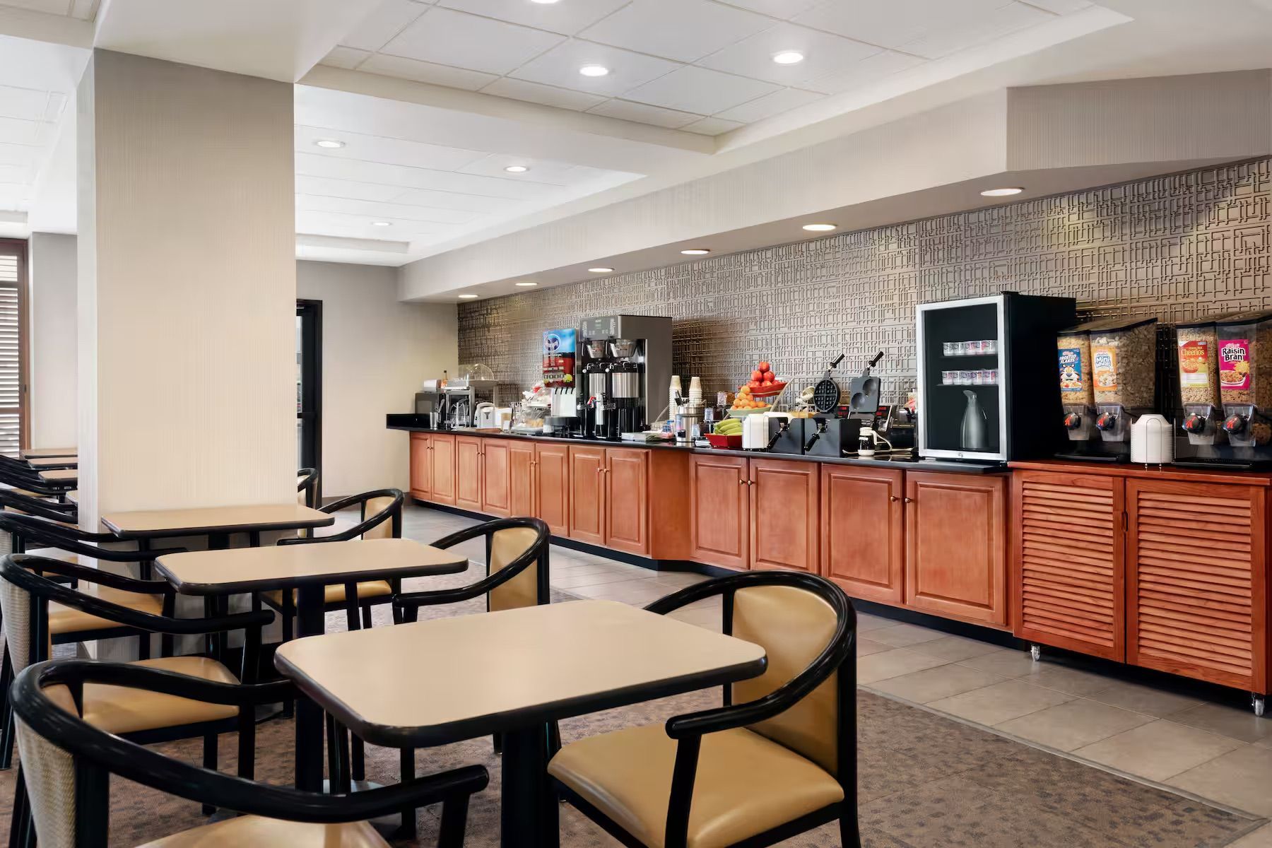 A hotel dining room with tables and chairs and a buffet.