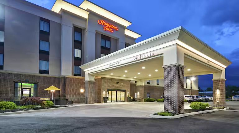Hampton Inn hotel exterior with illuminated entrance canopy and parking lot.