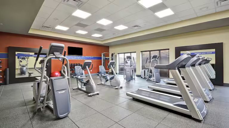 Hotel gym with treadmills, elliptical, stationary bikes, and a TV.