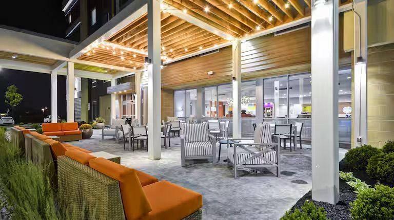 Outdoor patio with seating and lighting, next to a building at night.