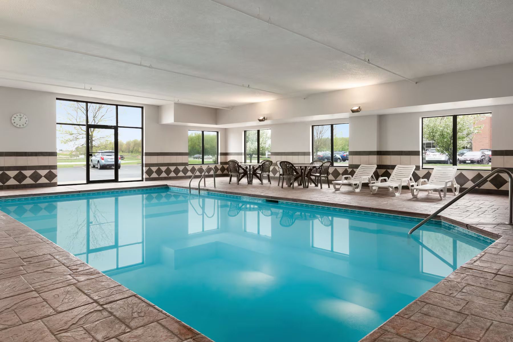 There is a large indoor swimming pool with chairs around it.